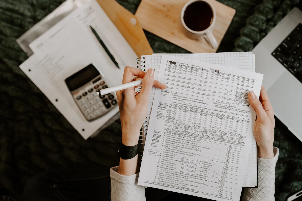 Pessoa analisando documentos financeiros com uma calculadora sobre a mesa.